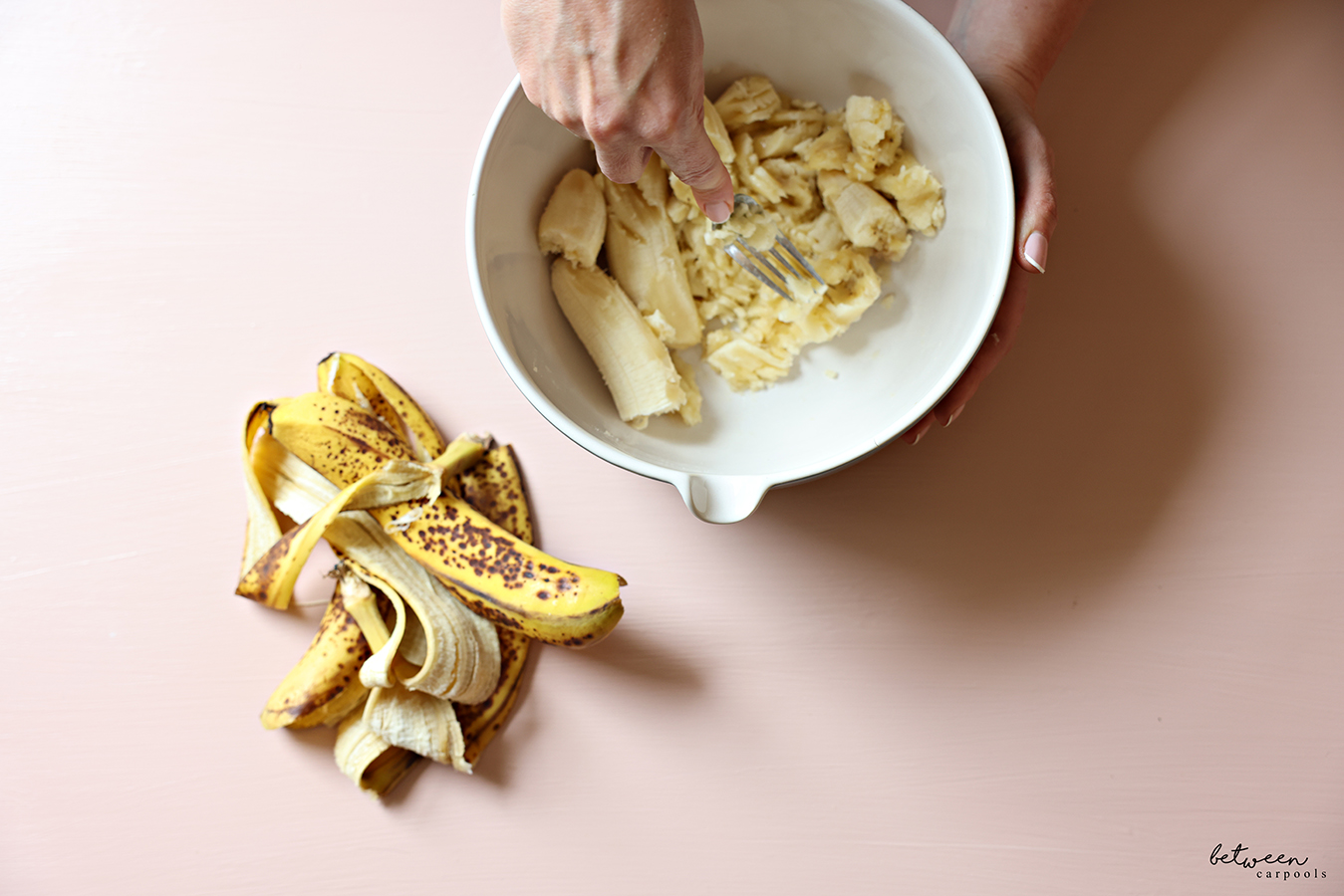 Mashing 3 overripe bananas in a mixing bowl.