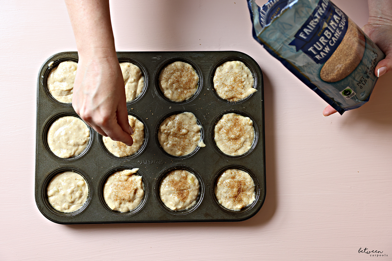 Topping each banana muffin in the cup of a standard 12 cup muffin pan with turbinado sugar.