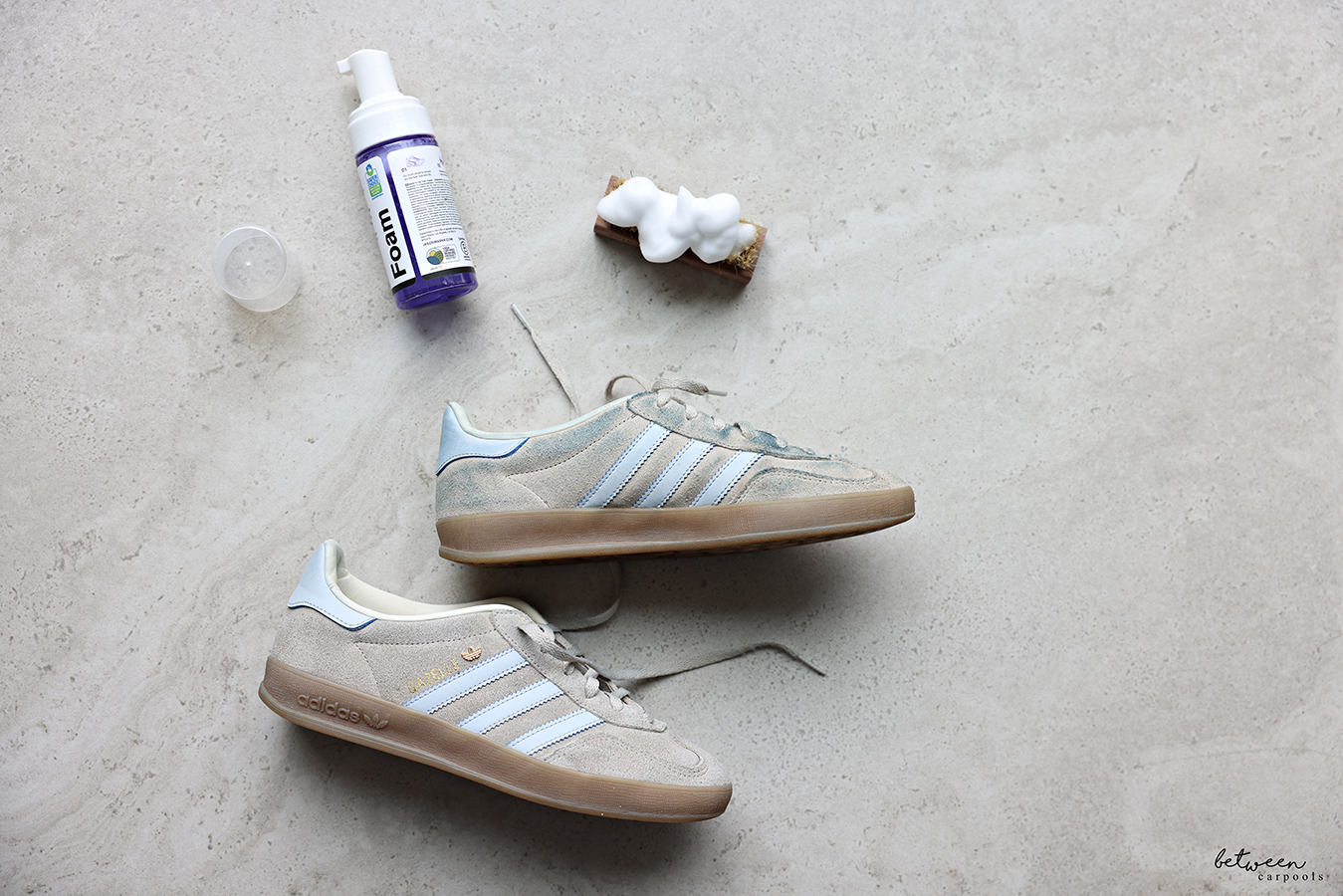 Jason Markk foaming cleaner on a soft bristle brush near a pair of adidas GAZELLE sneakers.