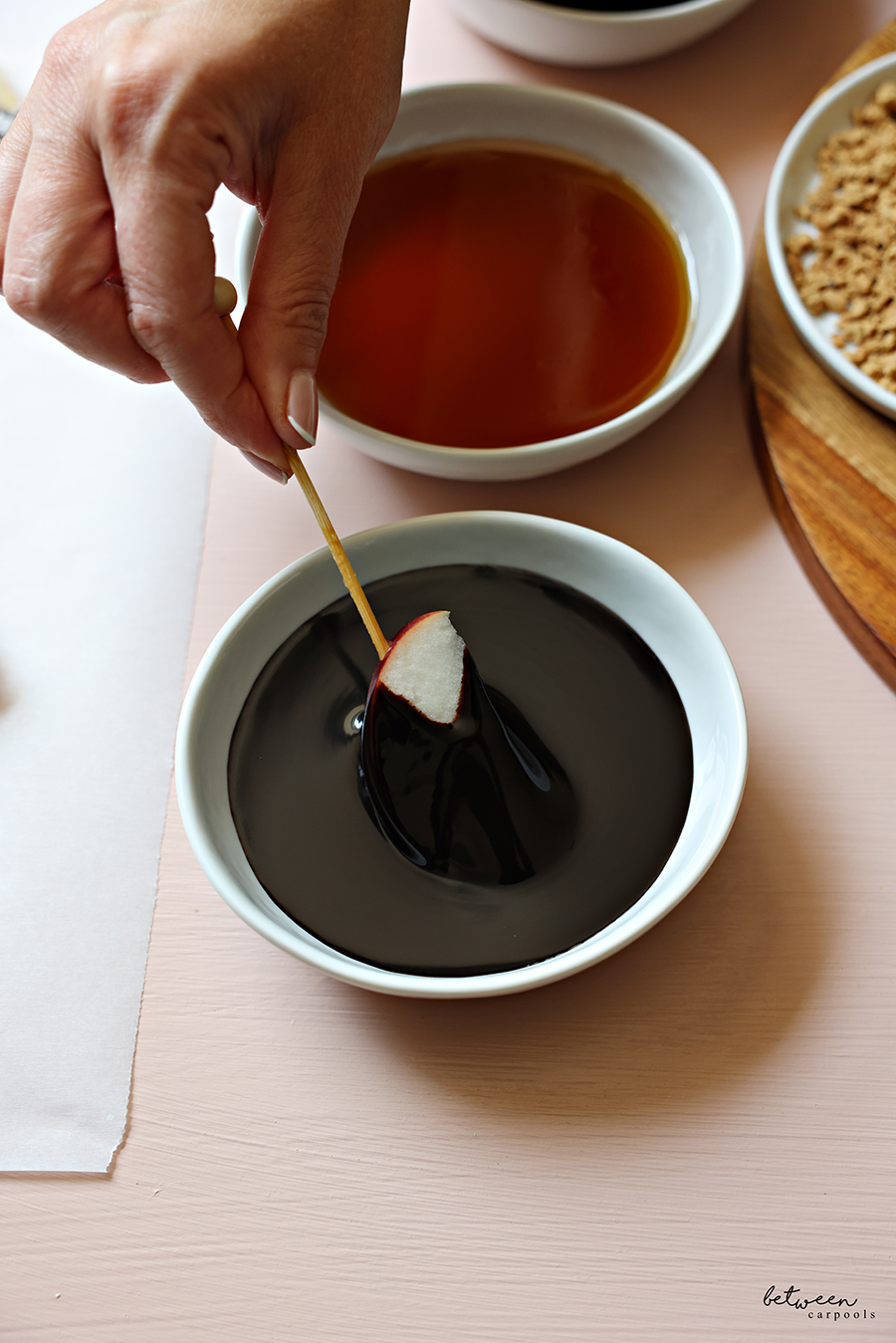 Dipping one skewered apple spear in chocolate sauce.